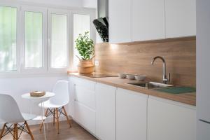 a kitchen with white cabinets and a sink and a table at Magno Apartments Miño in Seville