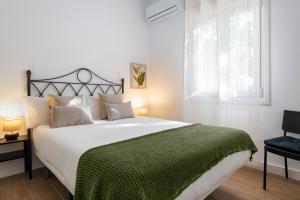 セビリアにあるMagno Apartments Miñoのベッドルーム(白い大型ベッド、緑の毛布付)