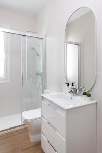 a white bathroom with a sink and a mirror at Magno Apartments Miño in Seville