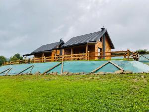 a log cabin with a house on top of a field at Domki Oaza Ciszy in Polańczyk