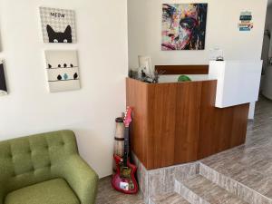 ein Zimmer mit einem grünen Stuhl und einer Gitarre neben einer Wand in der Unterkunft Family Hotel Dreams in Sozopol