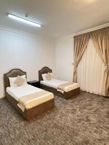 een hotelkamer met 2 bedden en een raam bij غزالي للوحدات السكنية in Al Madinah