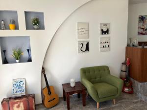 una sala de estar con una silla verde y una guitarra en Family Hotel Dreams, en Sozopol