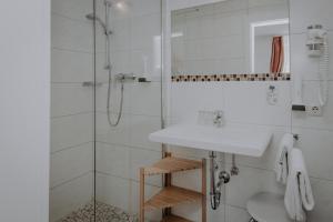 ein weißes Bad mit einem Waschbecken und einer Dusche in der Unterkunft Sporthotel Kitz in Bruck an der Großglocknerstraße