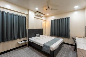 a bedroom with a large bed with black curtains at Hotel Ellora Park in Pune
