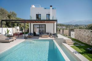 a villa with a swimming pool and a house at Avrilia Seaside Villa HEATED POOL in Almyrida