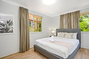 ein Schlafzimmer mit einem großen Bett und zwei Fenstern in der Unterkunft Marsfield 5 bed Townhouse near Macquarie Uni FreeP in Sydney