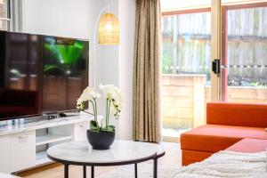 ein Wohnzimmer mit einem TV und einem Tisch mit Blumen darauf in der Unterkunft Marsfield 5 bed Townhouse near Macquarie Uni FreeP in Sydney