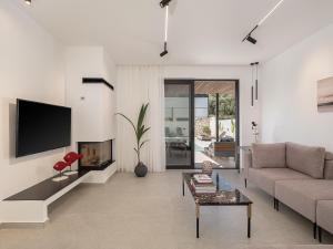 a living room with a couch and a tv at Avrilia Seaside Villa HEATED POOL in Almyrida
