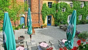 a patio with tables and umbrellas in front of a building at Up Hus Hotel Neuruppin in Neuruppin