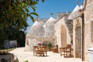 una vista esterna di una casa in pietra con tavolo e sedie di Trulli Macco Macco a Lamie di Olimpia