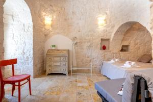una camera con due letti e un comò in una parete in pietra di Trulli Macco Macco a Lamie di Olimpia
