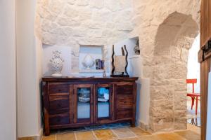 una camera con un mobile in legno in un muro di pietra di Trulli Macco Macco a Lamie di Olimpia