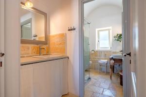 un bagno con lavandino e doccia con specchio di Trulli Macco Macco a Lamie di Olimpia Altre 21 foto