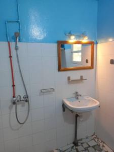 y baño con lavabo y ducha con espejo. en KONE-METTLER GUEST HOUSE en Abémé