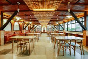 a dining room with tables and chairs and windows at WangChang Hotel Chiang Mai โรงแรมวังช้าง เชียงใหม่ in Chiang Mai