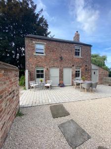 a brick house with a patio in front of it at Grooms Cottage next to Sheriff Hutton Castle in Sheriff Hutton