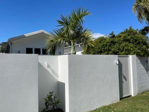 a white fence with a gate in front of a house at Sunny Palm Cottage Byron Bay - Brand New in Byron Bay