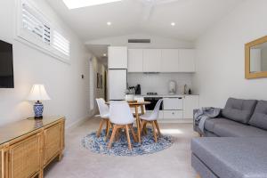 a living room with a couch and a table and chairs at Sunny Palm Cottage Byron Bay - Brand New in Byron Bay