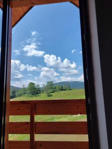 a window view of a field from a porch at Domek Rodakówka in Krempna