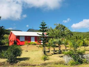una casa roja con un árbol delante en Location Villa pleine Nature Domaine des Radiers, en Sainte-Rose