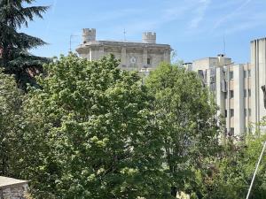 un bâtiment avec une tour d'horloge derrière quelques arbres dans l'établissement Chez Hélène, calme et verdure au centre historique, à Vincennes