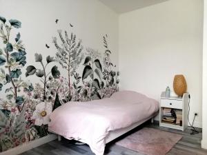 - une chambre avec un lit orné d'une fresque murale florale dans l'établissement L'Eau Vive, à Dinan