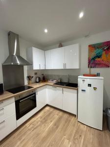 a kitchen with white cabinets and a white refrigerator at LESLIELOU T2 in La Ciotat