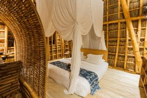 a bedroom with a bed with a canopy at Bambu Indah in Ubud