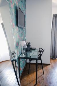 a glass desk with a lamp and a television on a wall at Le Manoir Hôtel in La Rochelle