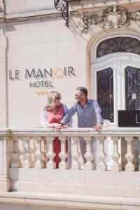 Le Manoir Hôtel في لا روشيل: رجل وامرأة يقفان على شرفة مبنى