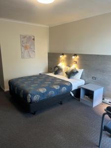 a bedroom with a large bed and a table at Colac Central Motel in Colac