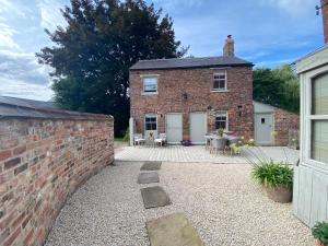 a brick house with a patio in front of it at Grooms Cottage by Sheriff Hutton Castle near York in Sheriff Hutton +40 photos