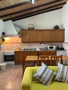a living room with a yellow couch and a kitchen at Casa dos AVÓS in Santana de Cambas