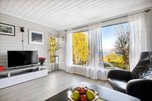 een woonkamer met een televisie en een groot raam bij Hytte i Saltstraumen in Bodø