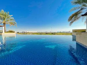 Voyage Ansam Three Bedroom With Ocean Views في أبوظبي: مسبح بالماء الأزرق والنخيل