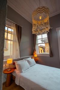 a bedroom with a white bed and a chandelier at Ivy Ayvalık Butik Otel in Ayvalık