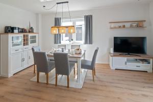 a dining room with a table and chairs and a television at Knus in Dornum +25 photos