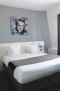 a bedroom with a bed with a painting on the wall at Le Manoir Hotel, BW Signature Collection in La Rochelle