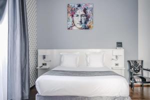 a bedroom with a white bed and a painting on the wall at Le Manoir Hotel, BW Signature Collection in La Rochelle