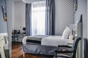 a bedroom with a bed and a window and a chair at Le Manoir H&ocirc;tel in La Rochelle