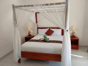 a bedroom with a canopy bed with white curtains at OkaOki Homestay in Amed