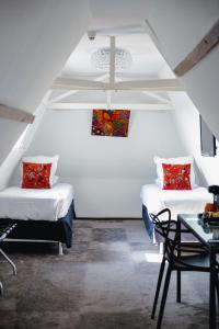 two beds in a white room with a table and chairs at Le Manoir Hôtel in La Rochelle