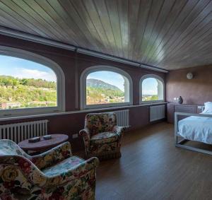 - une chambre avec un lit, 2 chaises et des fenêtres dans l'établissement Villa Agnona Appartamento in Villa, à Borgosesia