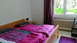 Cama con edredón púrpura en habitación con ventana en Ferienwohnungen Nohner Mühle en Nohn