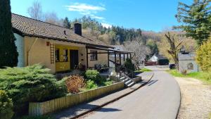 a house with a yellow door and a road at Ferienwohnungen Nohner Mühle in Nohn