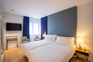 a bedroom with a large white bed with blue walls at abba Apartments Playa de Gros San Sebastián in San Sebastián