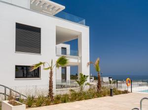 uma casa branca com palmeiras em frente ao oceano em Links II Sea & SPA by JC Homes em Alcaidesa