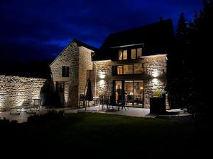 a stone house with lights on it at night at Maison d'hôte avec sauna et jacuzzi à la campagne in Les Portes du Coglais