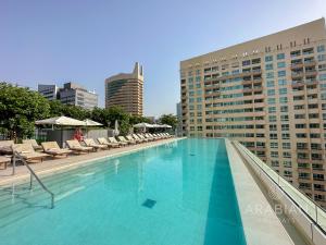 einen Pool mit Liegestühlen und ein Gebäude in der Unterkunft BRAND-NEW 1 Bedroom with full Marina View in Dubai